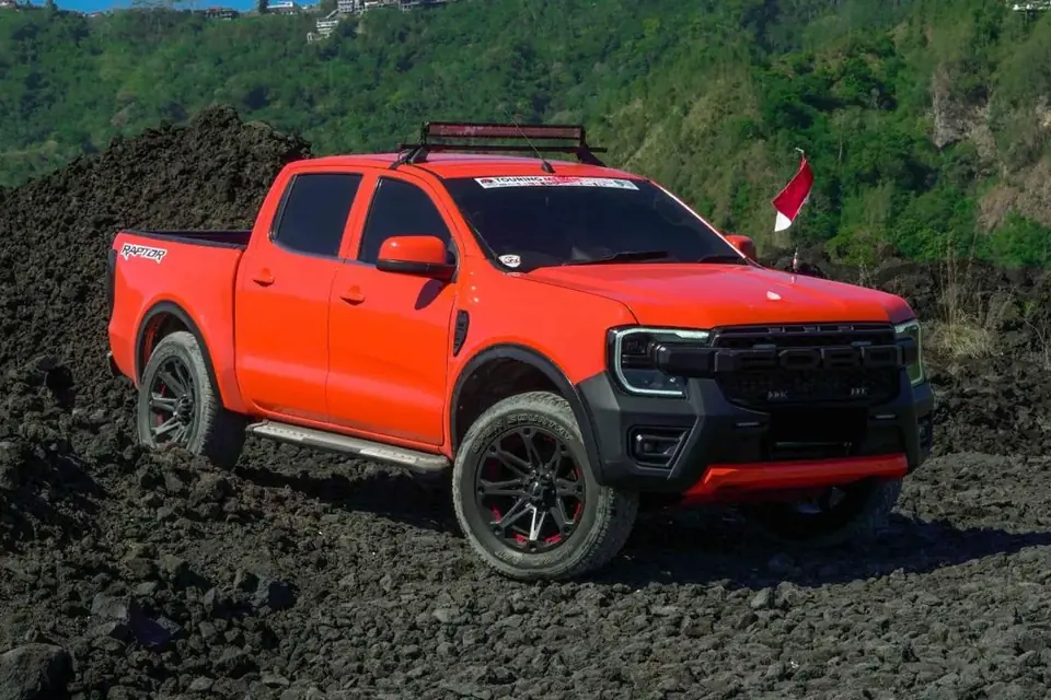 Orange Ford Raptor pickup on black lava ground