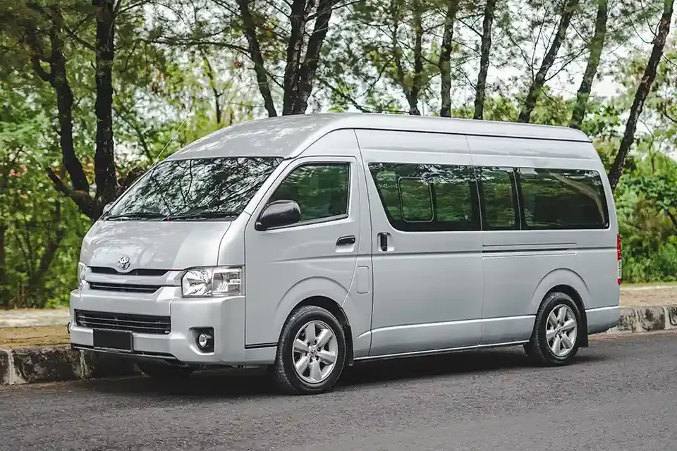 Silver Toyota Hi Ace Commuter van on a tree-lined road