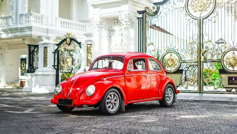 Red classic VW Beetle (Kodok) at a villa gate