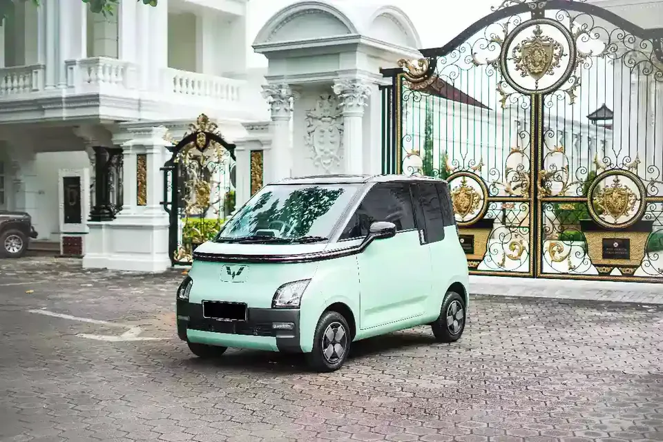 Mint green Wuling Air EV parked outside a villa gate in Bali